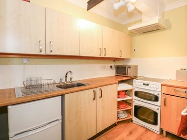 A kitchen with wooden cabinets a white stove a microwave a sink and a small refrigerator at 16 Norfolk Heights Docking