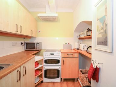 A kitchen with a white oven, microwave, countertop appliances, and wooden cabinets at 16 Norfolk Heights in Docking