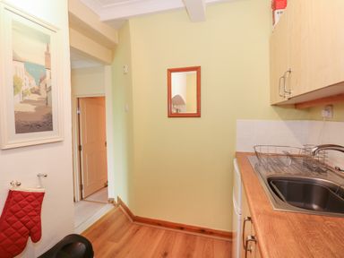 A kitchen area with a sink and dish rack on a wooden countertop and a mirror on the wall at 16 Norfolk Heights in Docking
