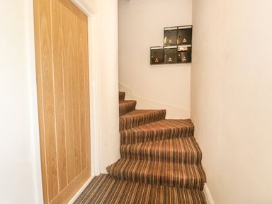 A small hallway with striped carpeted stairs and black mailboxes on the wall at 16 Norfolk Heights in Docking