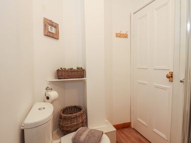 A small bathroom with a toilet a basket a towel on the toilet and a framed picture on the wall at 16 Norfolk Heights in Docking