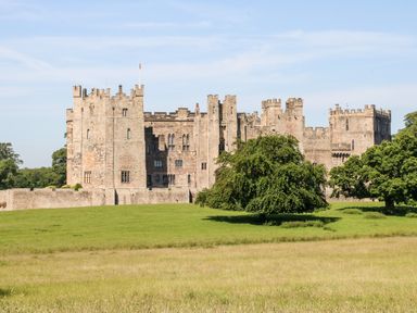 A stone castle with multiple towers on a grassy field with trees at Foxes Den in Winston near Staindrop