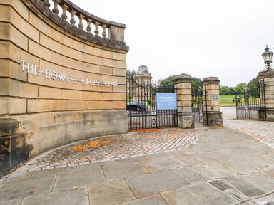 The entrance gate to The Bowes Museum with a stone wall and iron gates at Foxes Den in Winston near Staindrop