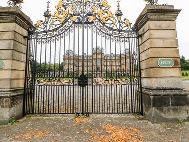 Ornate black and gold gates with stone pillars and a large stately building in the background at Foxes Den in Winston near Staindrop