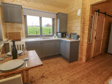 A kitchen with grey cabinets and a wooden dining table set for two at Foxes Den in Winston near Staindrop