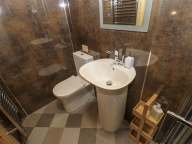 A bathroom with a toilet pedestal sink mirror towel rack and wooden storage unit at Foxes Den Winston near Staindrop