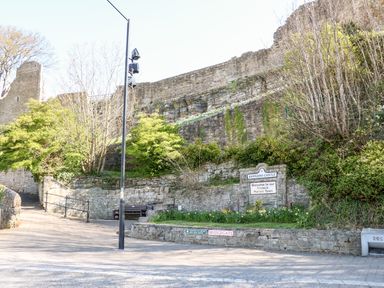 An outdoor scene with stone walls trees and a sign for Barnard Castle in a historic market town