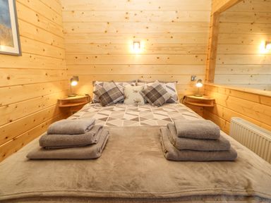 A bedroom with a bed with geometric patterned bedding and folded towels on top at Otters Holt in Winston near Staindrop