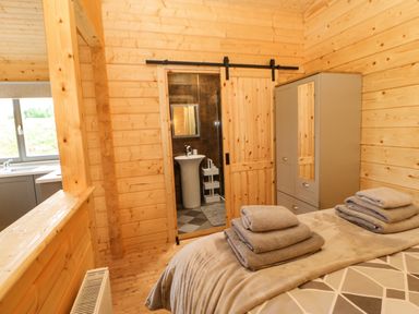 A bedroom with folded towels on bed a wardrobe and a sliding door leading to a bathroom at Otters Holt in Winston near Staindrop