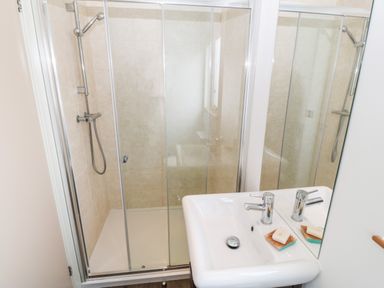 A bathroom with a glass shower enclosure and a white sink with a bar of soap at Sunstone Lodge Garreg Haul Lodge in Cilan near Abersoch