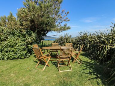 A garden with a table and wooden chairs at Sunstone Lodge (Garreg Haul Lodge) Cilan near Abersoch