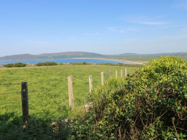A view of a landscape with a fence and water at Sunstone Lodge (Garreg Haul Lodge) in Cilan near Abersoch