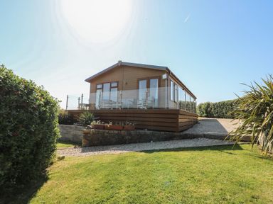 A lodge with glass railing and plants at Sunstone Lodge (Garreg Haul Lodge) Cilan near Abersoch