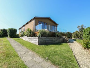 A house with a pathway and grass area at Sunstone Lodge (Garreg Haul Lodge) in Cilan near Abersoch