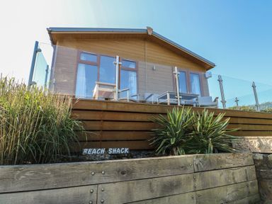 A lodge with a balcony and a wooden deck at Sunstone Lodge (Garreg Haul Lodge) Cilan near Abersoch