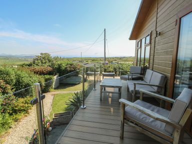 A deck with seating and garden at Sunstone Lodge (Garreg Haul Lodge) Cilan near Abersoch