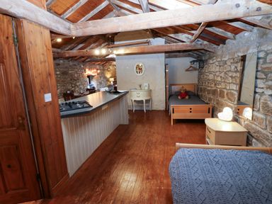 A bedroom with a bed and kitchen area at The Granary in Rothbury
