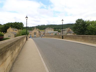 A street view with a bridge and buildings at The Granary in Rothbury