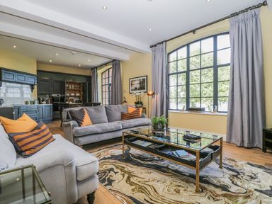 A living room with gray sofas orange striped pillows a glass coffee table and large window at Tarn End Cottages 5 Talkin near Brampton Cumbria