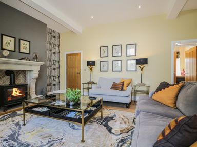 A living room with sofas a glass coffee table a fireplace and framed pictures on the wall at Tarn End Cottages 5 in Talkin near Brampton Cumbria