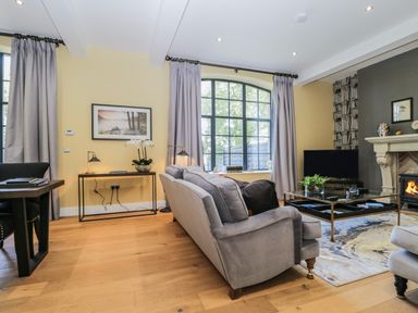 A living room with a gray sofa facing a fireplace and television at Tarn End Cottages 5 Talkin near Brampton Cumbria
