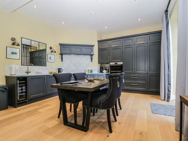 A kitchen with dark cabinets a dining table with chairs and wooden flooring at Tarn End Cottages 5 Talkin near Brampton Cumbria