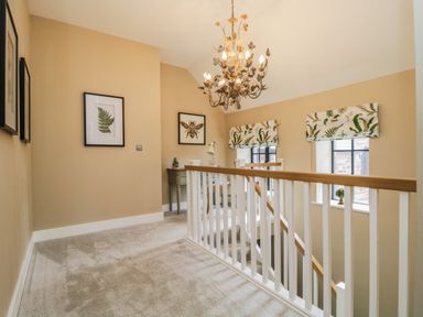 A stairway landing with framed artwork a chandelier and windows with patterned blinds at Tarn End Cottages 5 Talkin near Brampton Cumbria