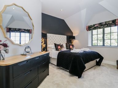 A bedroom with a bed, black dresser with mirror, and window with floral blinds at Tarn End Cottages 5 Talkin near Brampton Cumbria