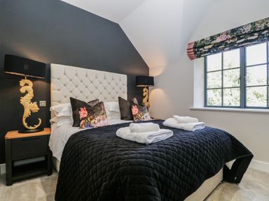 A bedroom with a bed with floral pillows and folded towels on a black quilt at Tarn End Cottages 5 Talkin near Brampton Cumbria