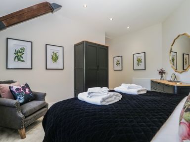 A bedroom with a black wardrobe and a black bedspread with towels on the bed at Tarn End Cottages 5 Talkin near Brampton Cumbria