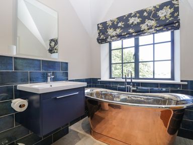 A bathroom with a freestanding metallic bathtub and a sink under a mirror at Tarn End Cottages 5 Talkin near Brampton Cumbria