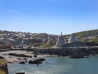 A coastal town with houses near the shoreline and large conical structures by the water at Beech Cottage in Combe Martin
