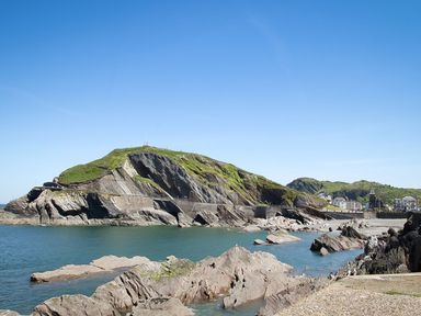 Rocky coastline with a hill and buildings near the water at Combe Martin