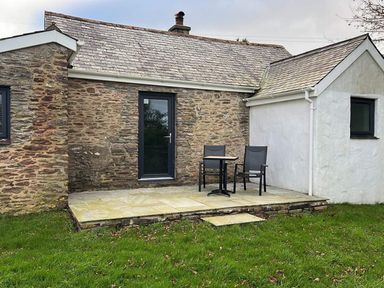 A stone cottage with a small paved patio and two chairs with a table on the patio at Beech Cottage in Combe Martin