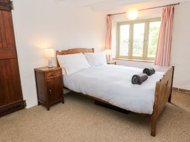 A bedroom with a wooden bed and two bedside tables with lamps at Porth Farm Annexe Mawgan Porth