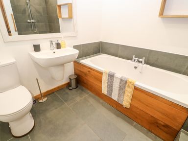 A bathroom with a toilet sink and bathtub with a striped towel at Porth Farm Annexe in Mawgan Porth