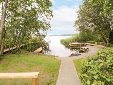 A lakefront area with wooden docks and a pathway surrounded by trees at Port Heron Lodge in Ballykeeran near Glasson County Westmeath