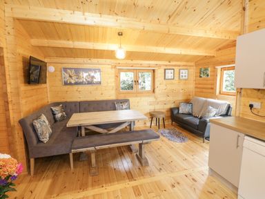 A wooden cabin interior with a dining table and bench seating a sofa and kitchen cabinets at Port Heron Lodge Ballykeeran near Glasson County Westmeath