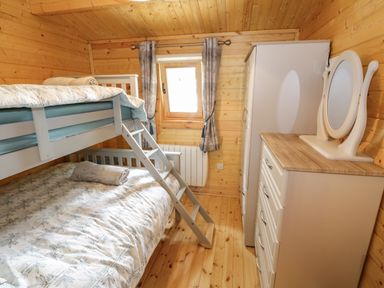 A wooden bedroom with bunk beds a window with curtains a white dresser with mirror and wardrobe at Port Heron Lodge Ballykeeran near Glasson County Westmeath