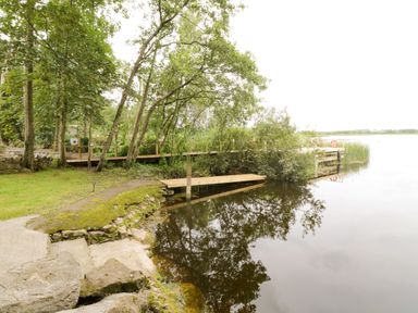 A riverside area with trees a wooden dock and a stone path at Port Heron Lodge Ballykeeran near Glasson County Westmeath