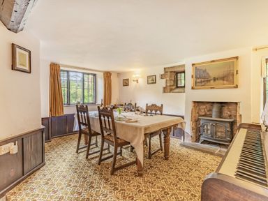 A dining room with a table and chairs a fireplace and a piano at Saint Pancras Chapel in Washford near Williton