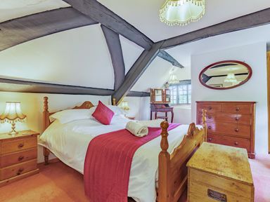 A bedroom with a wooden bed a chest of drawers a wooden trunk and a dressing table at Saint Pancras Chapel in Washford near Williton