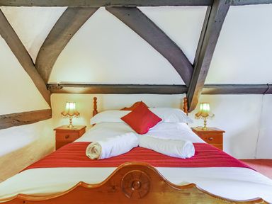 A bedroom with a wooden bed with white and red bedding and two bedside tables with lamps at Saint Pancras Chapel in Washford near Williton