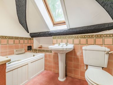A bathroom with a bathtub, sink, toilet, and a skylight window at Saint Pancras Chapel in Washford near Williton