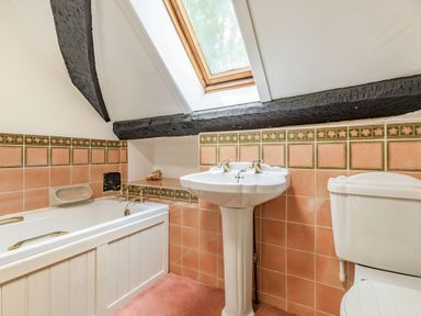 A bathroom with a bathtub sink toilet skylight window and tiled walls at Saint Pancras Chapel in Washford near Williton