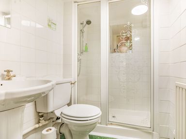 A bathroom with a sink, toilet, toilet paper roll, and a shower with glass doors at Saint Pancras Chapel in Washford near Williton