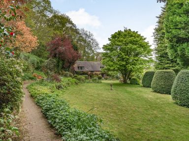 A garden with a lawn brick path shrubs and trees at Saint Pancras Chapel in Washford near Williton