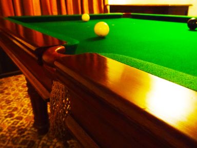 A pool table with balls on the green felt in a room with patterned carpet at Saint Pancras Chapel in Washford near Williton
