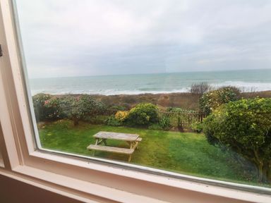 A garden with grass and a bench overlooking the ocean at Stonecroft in Praa Sands