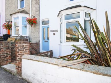 The exterior of a house with a blue door a bay window brick walls and plants outside at The Shambles in Fortuneswell